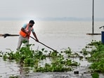 A municipal worker cleans a road inundated with floodwaters from the swollen Ganga river in Prayagraj on Sunday (PTI)