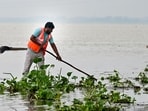 A municipal worker cleans a road inundated with floodwaters from the swollen Ganga river in Prayagraj on Sunday.