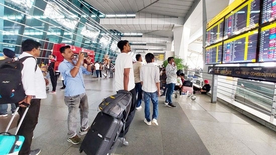 People wait outside the departure terminal at Indira Gandhi International (IGI) Airport, in New Delhi, on Friday.
