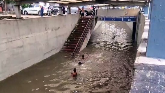 Children swim and play in a waterlogged area at Rajiv Chowk following continuous rainfall in Gurugram on Tuesday.