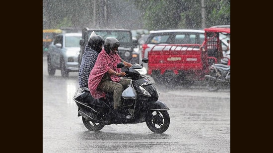 Commuters on their way during rain in Chandigarh on Tuesday. (Keshav Singh/HT)