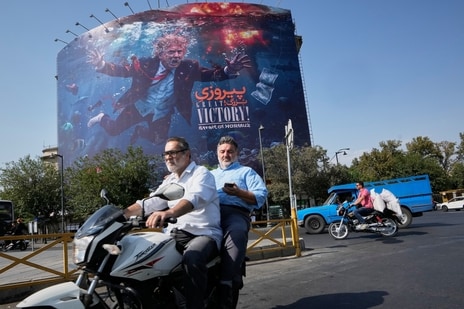 Motorcyclists pass a billboard depicting U.S. President Donald Trump underwater amid explosions, with the words "Great Victory! Strait of Hormuz," in Tehran, Iran, Monday, Aug. 24,