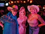 Fans of Dolly Parton pose with a cardboard cutout of the late singer-songwriter during a tribute night in her honor at a bar in Houston, Texas