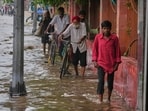 Pedestrians are seen wading though a flooded road after Yamuna overflowed in Delhi following heavy rain.(Manish Swarup/AP)
