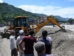 Residents gather along a road as workers use a bulldozer to clear mud and debris after flash floods in the Devighat area in Nepal's Nuwakot district.(AFP)