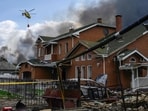 A damaged house as a firefighting helicopter carries a load of water to extinguish a fire at a warehouse following an air attack near Boryspil, Kyiv region on August 27, 2026, amid the Russian invasion of Ukraine.