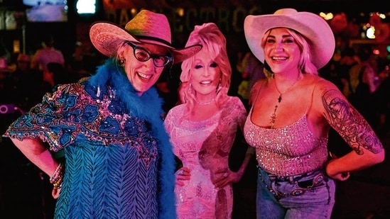 Fans of Dolly Parton pose with a cardboard cutout of the late singer-songwriter during a tribute night in her honor at a bar in Houston, Texas