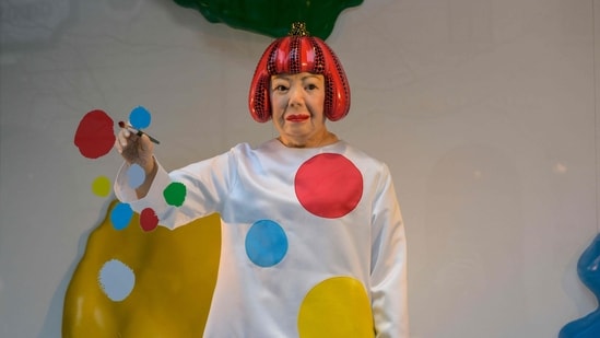 A life-like robot of artist Yayoi Kusama painting a window stands at the Louis Vuitton store on Fifth Avenue in New York City on January 13, 2023. (Photo by ANGELA WEISS / AFP)