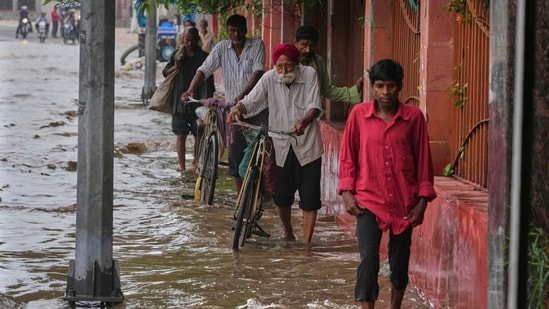 Pedestrians are seen wading though a flooded road after Yamuna overflowed in Delhi following heavy rain.
