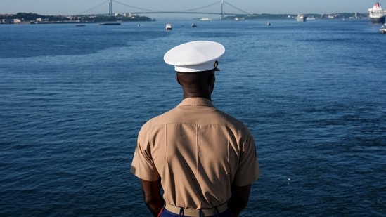 A member of the U.S. Marine Corps looks at the sea from aboard the Wasp-class amphibious assault ship USS Kearsarge Navy ahead of the Sail 250 parade of ships in New York Harbor,