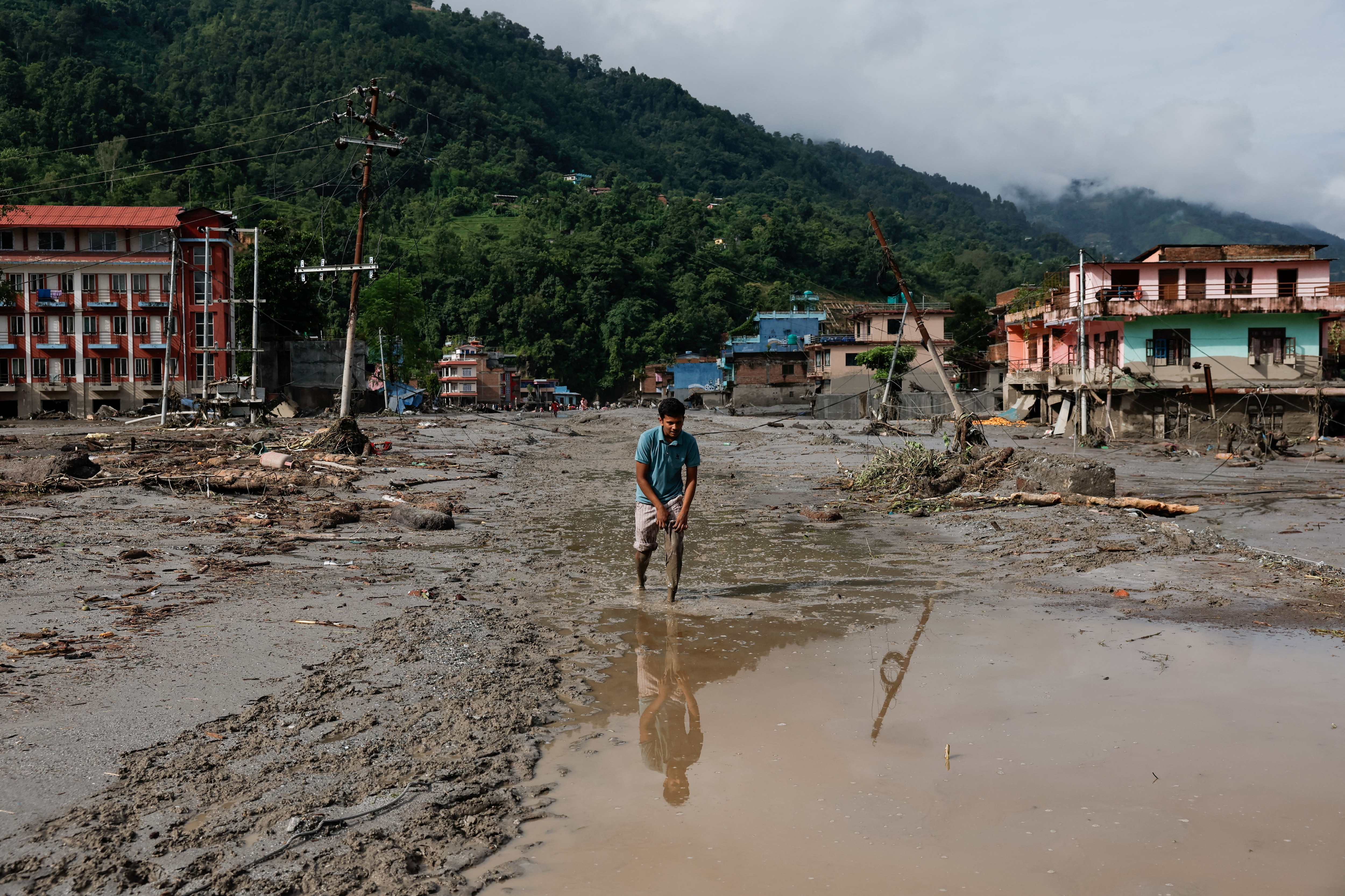 A man wades through muddy waters following devastating floods, in Trishuli in Nuwakot district, Nepal. (REUTERS)