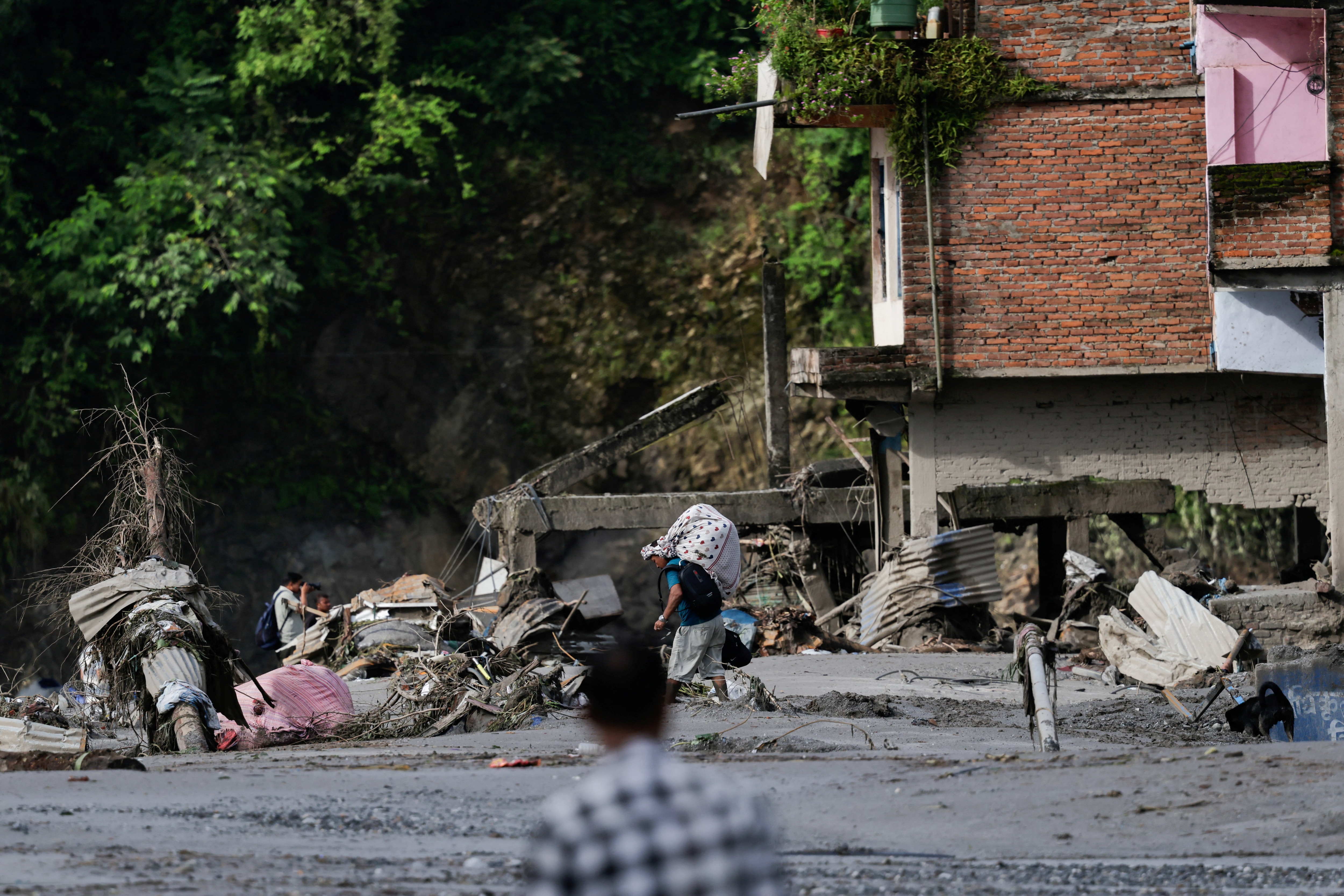 A man carrying his belongings moves through the debris following devastating floods, in Trishuli in Nuwakot district, Nepal. REUTERS