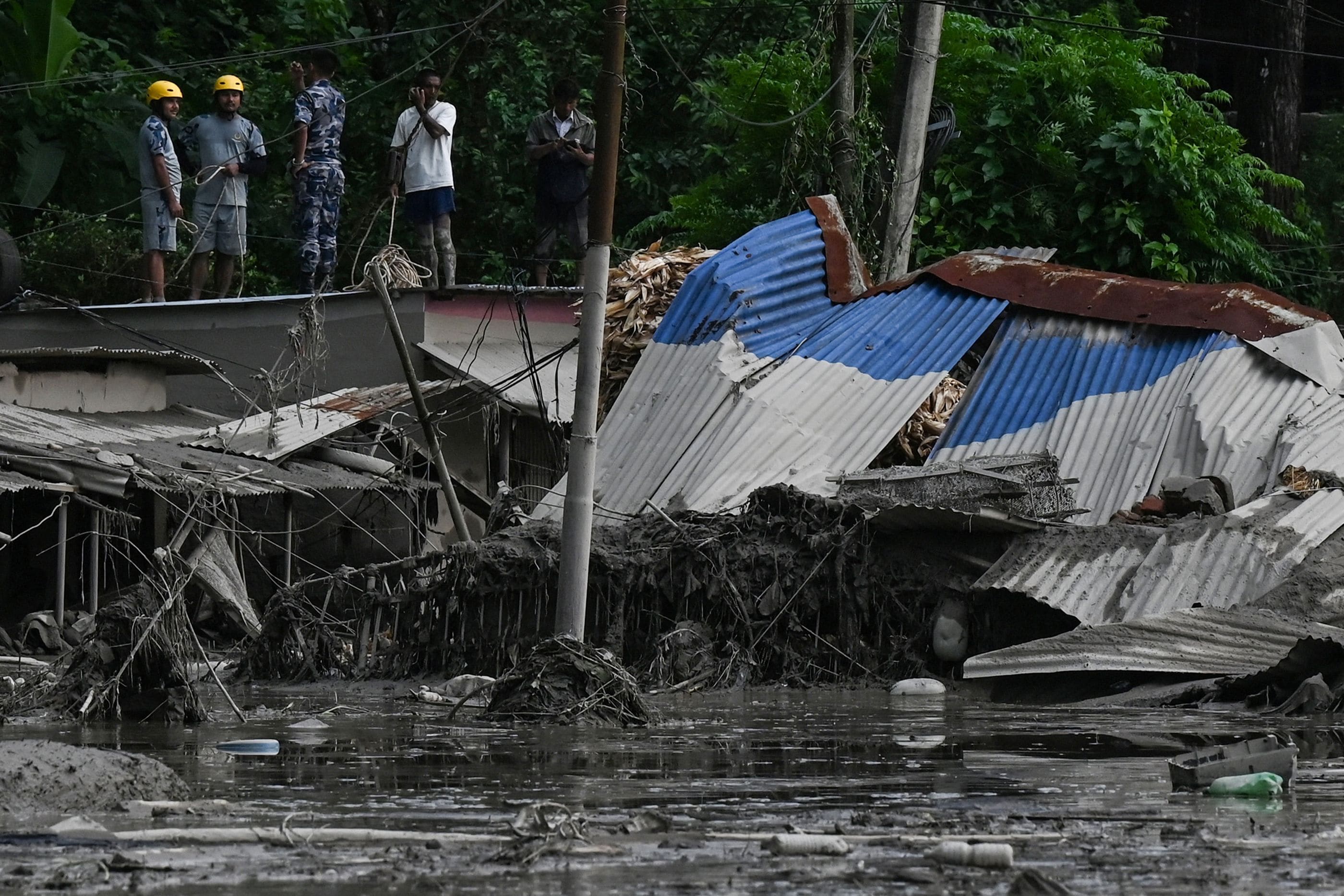 Rescuers look for survivors among the mud and the rubbles of buildings following flash floods and a landslide disaster in in Devghat, in Nepal's Nuwakot district.