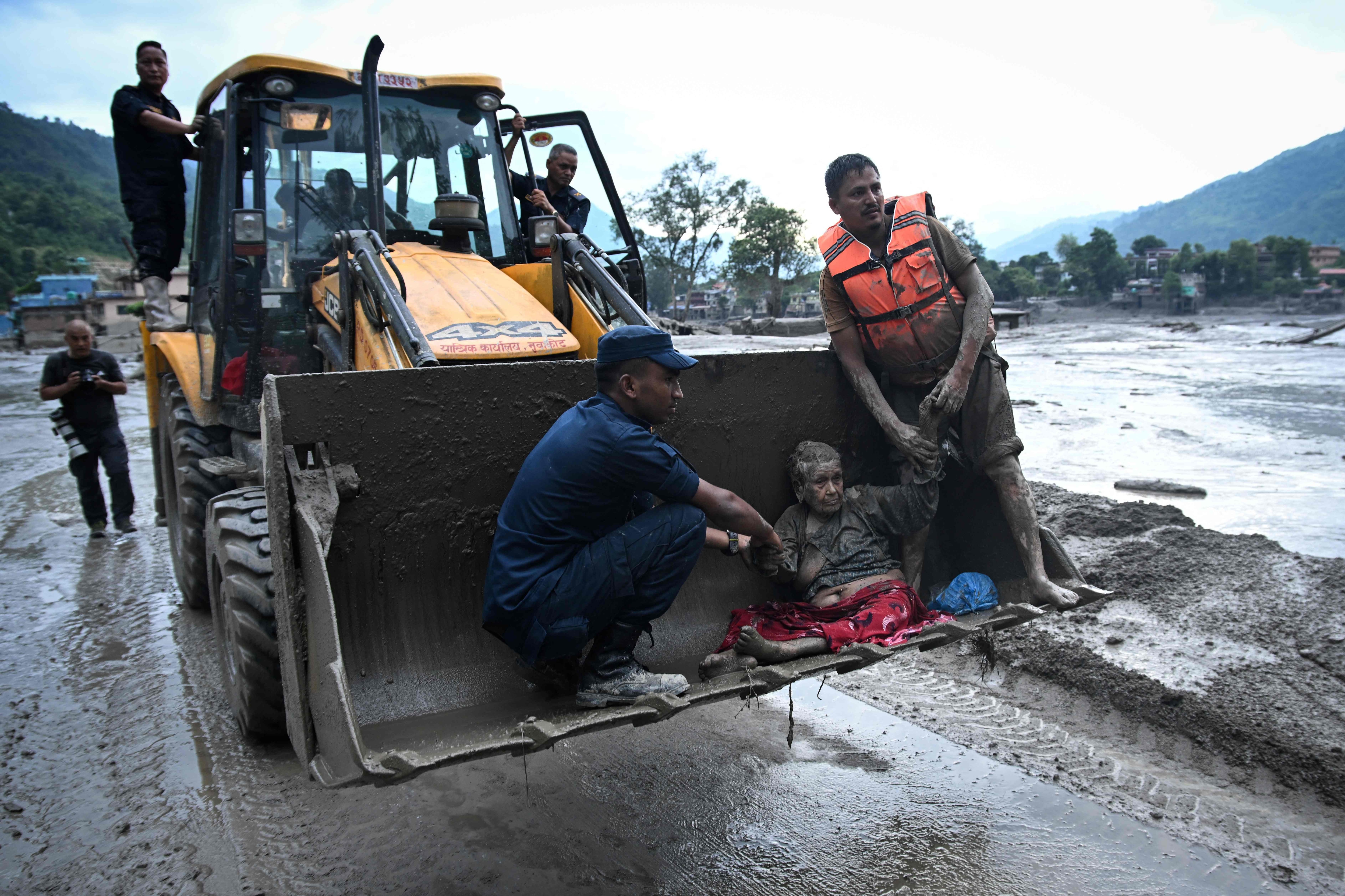 Rescuers use an excavator to transport a flood survivor, following flash floods and a landslide disaster in Devghat, in Nepal's Nuwakot district.