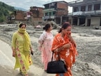 Women cover their faces to avoid a foul smell as they walk past damaged structures after flash flooding in the Devighat area of Nuwakot district in Nepal, Friday, Aug. 28, 2026.(AP Photo/Rajesh Kumar Singh)