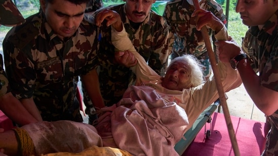 Nepal floods LIVE: An elderly survivor is taken to a makeshift hospital for treatment at the army's Maithali barracks after being rescued from flash flooding in Nuwakot district. (AP )