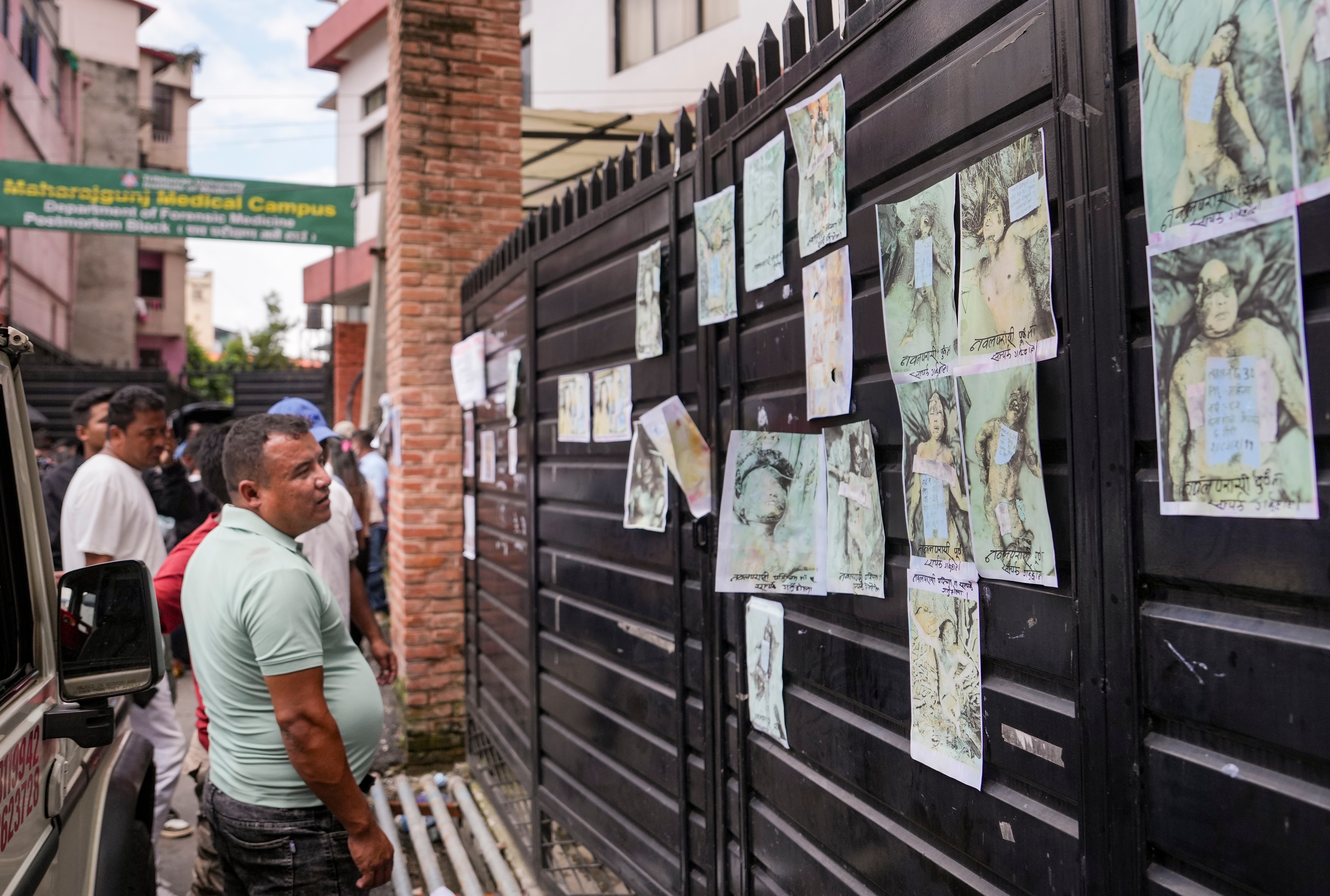 Family members and relatives look at photographs of victims displayed outside a morgue for identification in the aftermath of the flash floods, in Kathmandu. (PTI)
