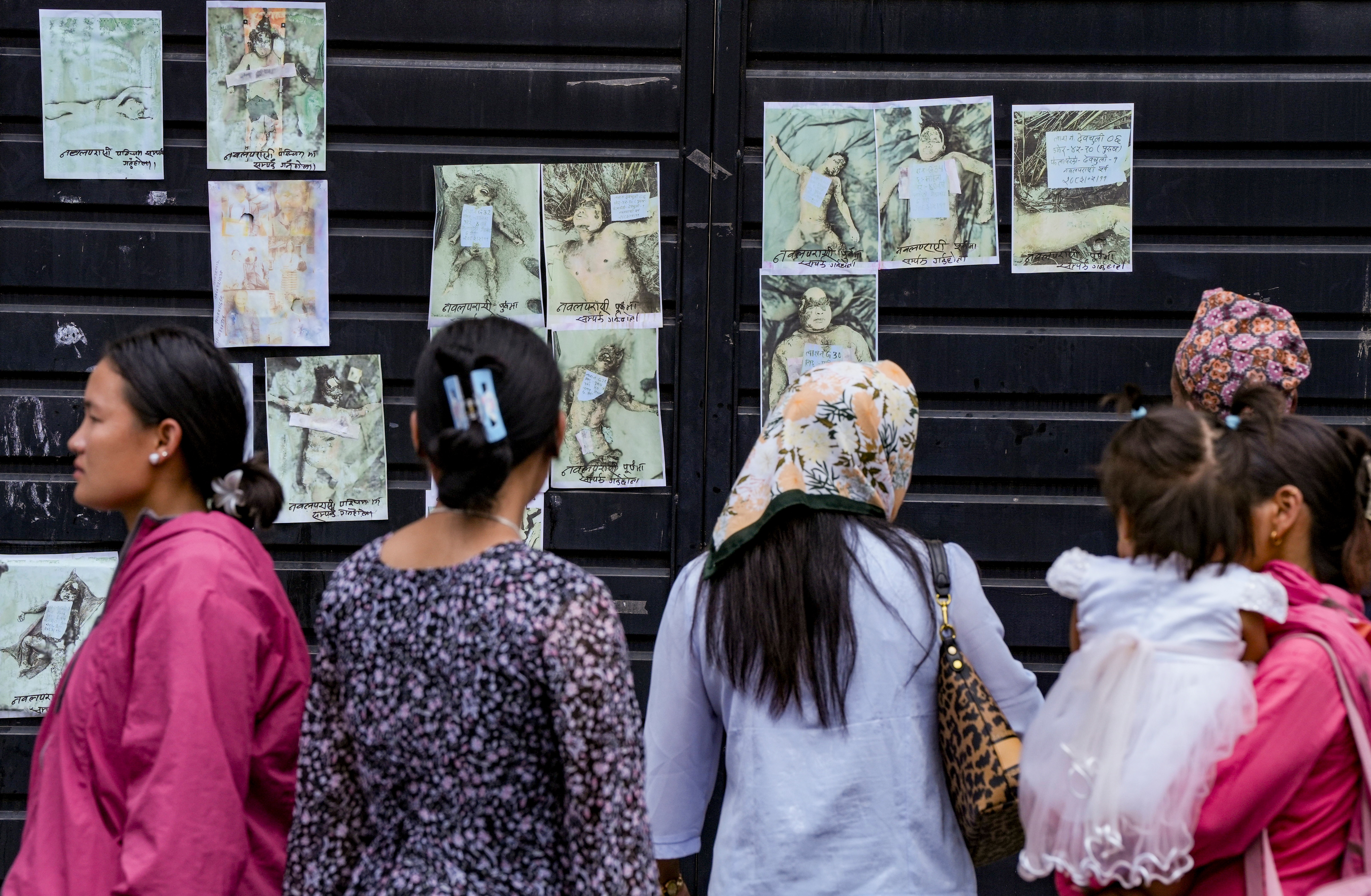 Family members and relatives look at photographs of victims displayed outside the morgue for identification in the aftermath of the flash floods, which originated in Tibet and swept through central Nepal, at Tribhuvan University Teaching Hospital. (PTI)