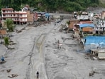 Aerial photograph showing people walking along a road in the middle of houses covered in sludge in the aftermath of flash floods at Devighat in Nepal's Nuwakot district. 