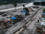 A drone view of people walking on a road and houses in mud, following deadly flash floods and mudslides at Devighat, Nuwakot district, Nepal.