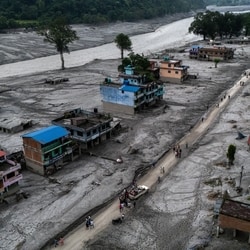 A drone view of people walking on a road and houses in mud, following deadly flash floods and mudslides at Devighat, Nuwakot district, Nepal.