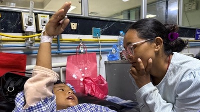 ఆసుపత్రిలో తల్లితో మాట్లాడుతున్న బాలుడు.. (REUTERS)
