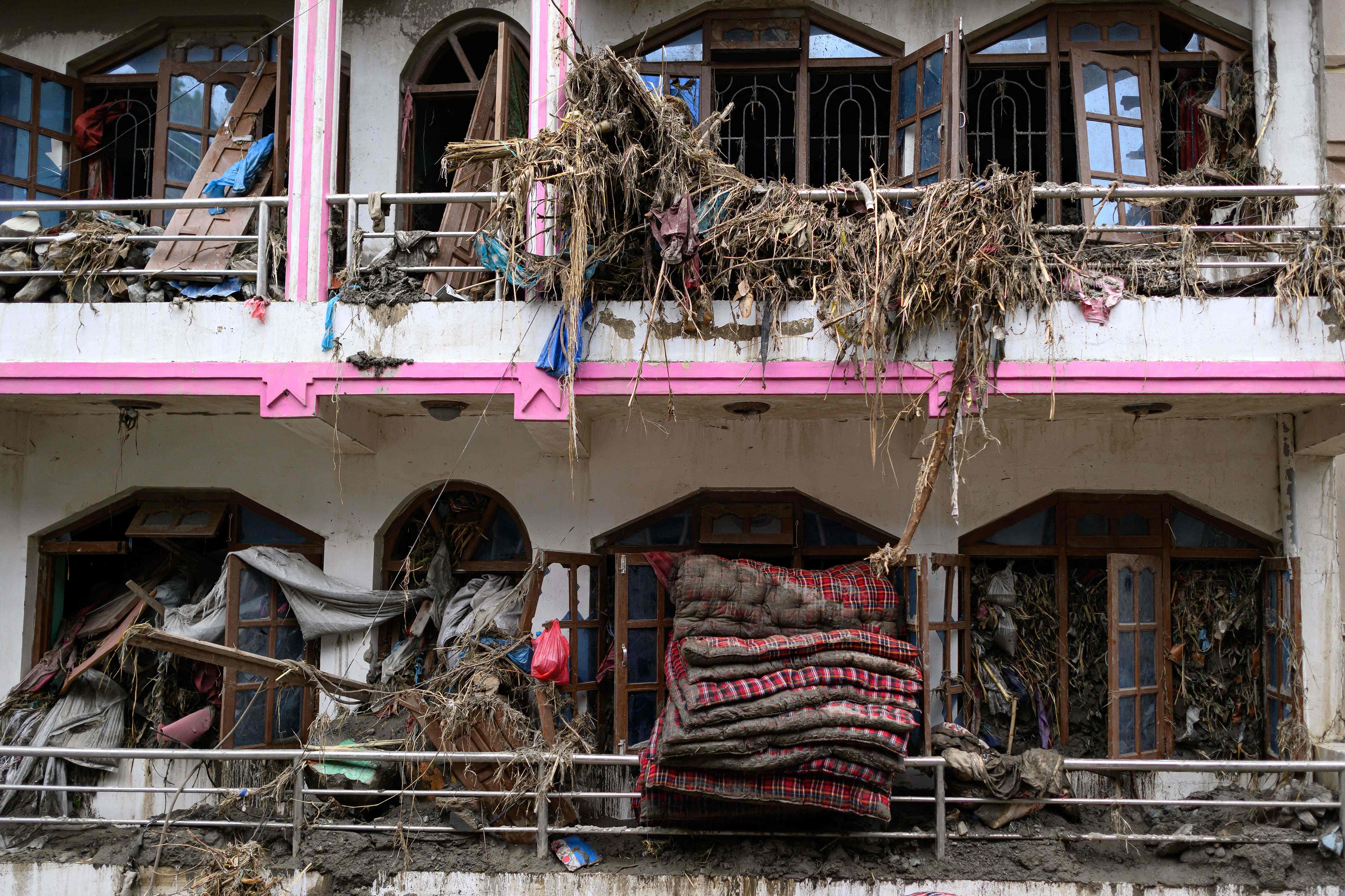 Mattresses and debris is seen coming out of windows of a damaged house in the aftermath of flash floods at Devighat in Nepal's Nuwakot district on August 29, 2026. (AFP)