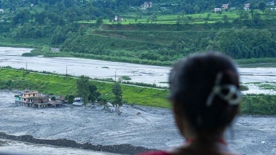 Nuwakot: People sit near a damaged structure as they look on the flood-ravaged Trishuli river in the aftermath of flash floods, at Trishuli market, in Nuwakot district, Sunday, Aug. 30, 2026.