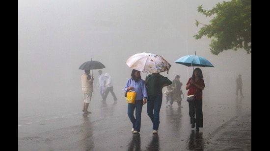 People walk amid mist and monsoon rainfall at the Ridge, in Shimla, Himachal Pradesh, on Sunday. (PTI)