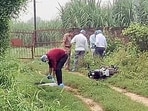 Forensic team and police personnel inspect the encounter site where a motorcycle lies on the ground in Shamli on Monday. (ANI VIDEO GRAB)