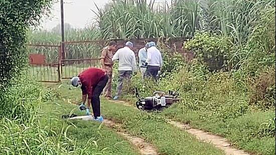 Forensic team and police personnel inspect the encounter site where a motorcycle lies on the ground in Shamli on Monday. (ANI VIDEO GRAB)