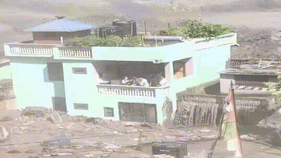 Despite the destruction after the floods, the green house stood erect, with its residents seen standing huddled in the balcony.