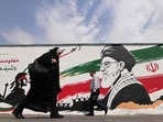 Pedestrians walk past a wall mural of Iran's slain supreme leader Ayatollah Ali Khamenei, along a street in downtown of Tehran on August 31.