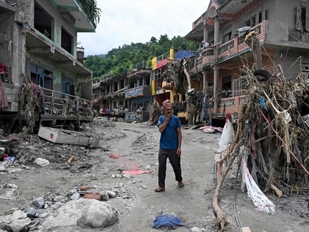 A man walks past damaged houses following flash floods at Devighat in Nepal's Nuwakot district. 