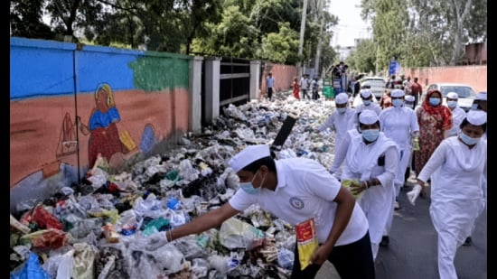 Members of the Congress Seva Dal spraying DPT on the garbage heaps at several locations in Rohtak. (HT Photo)