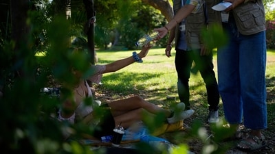 File photo: A woman living in a park receives cold water and a small hygiene kit from during heat wave in Athens, Greece (AP)