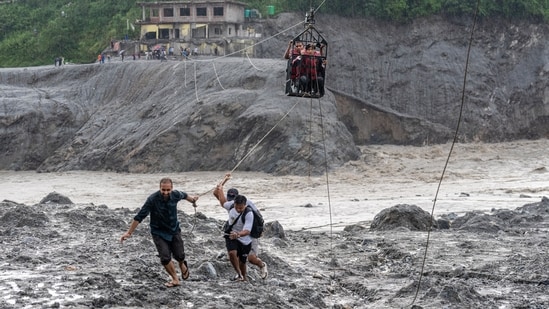 Residents pull the steel wire of a newly installed zipline to help people commute across the Trishuli River in the aftermath of flash floods at Bidur in Nepal's Nuwakot district, Nepal. 