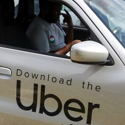 A Nigerian ride-hailing driver working with Uber sits inside his car and prepares to go offline.