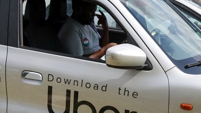 A Nigerian ride-hailing driver working with Uber sits inside his car and prepares to go offline. (REUTERS)