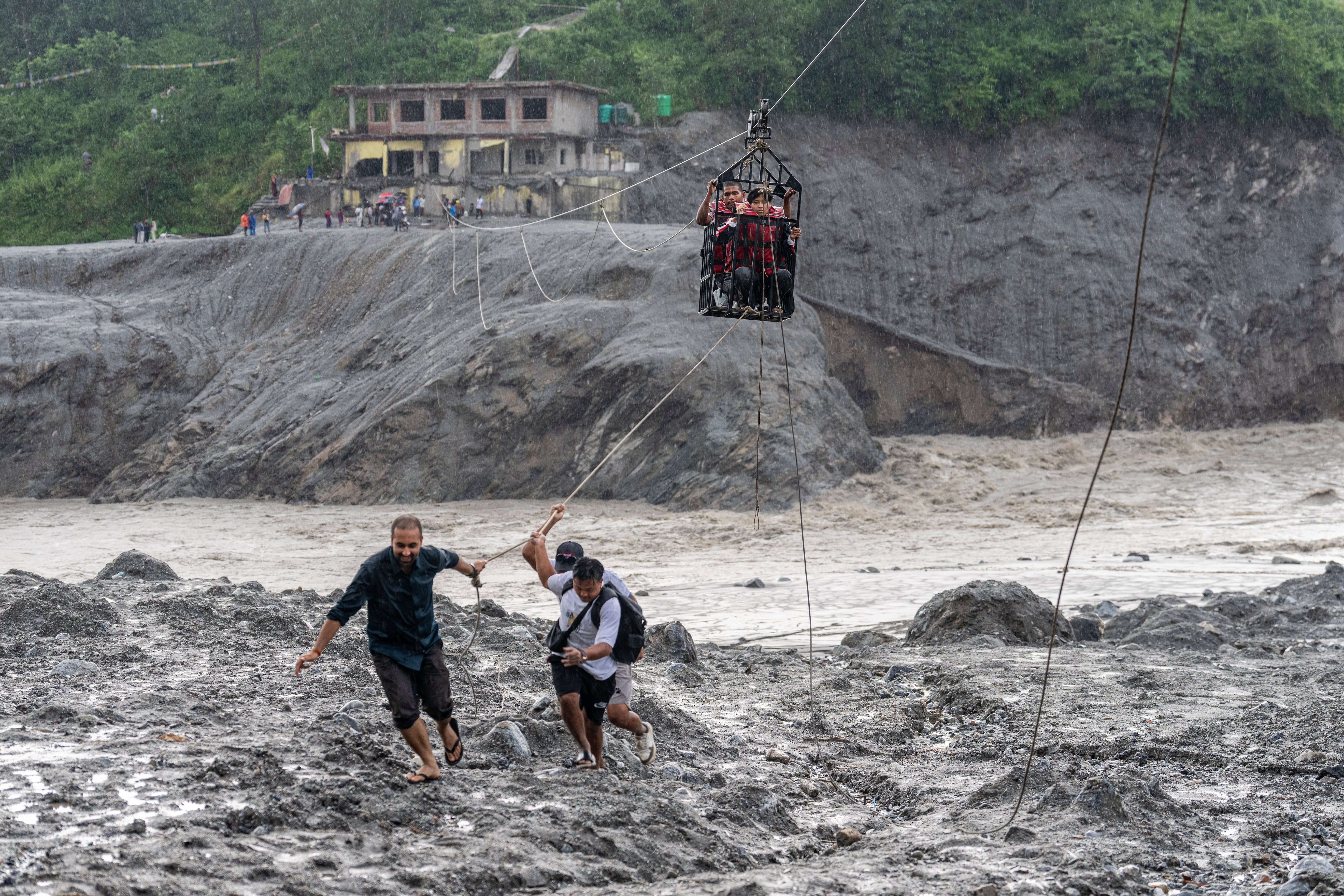 Residents pull a newly installed zipline to help people commute across the Trishuli river in the aftermath of flash floods at Bidur in Nepal's Nuwakot district, Nepal. (AP) Residents pull a newly installed zipline to help people commute across the Trishuli river in the aftermath of flash floods at Bidur in Nepal's Nuwakot district, Nepal. (AP)