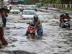Commuters wade through a water logged stretch at Mayur Vihar Phase 2 near NH24 amid heavy rains in New Delhi.