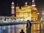 Women sit near the sarowar of the illuminated Golden Temple during a spell of monsoon rain, in Amritsar.