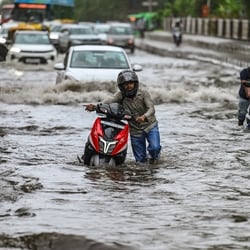 Commuters wade through a water logged stretch at Mayur Vihar Phase 2 near NH24 amid heavy rains in New Delhi.