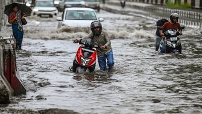 Commuters wade through a water logged stretch at Mayur Vihar Phase 2 near NH24 amid heavy rains in New Delhi. (RAJ K RAJ/HT Photo)