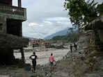 Residents walk past damaged houses covered in sludge in the aftermath of flash floods in Trishuli,