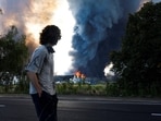 A man looks on as smoke rises over a warehouse, which was hit by a Russian drone strike, amid Russia's attack on Ukraine, in Kyiv region, Ukraine.