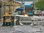 Commuters wade through a water logged stretch at Mayur Vihar Phase 2 near NH24 amid heavy rains in New Delhi on Friday. 