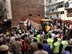 Members of rescue teams and police officers inspect the site and look for survivors after a building collapsed in New Delhi.