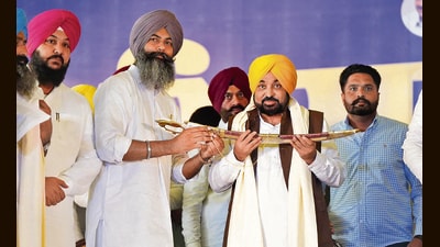 Punjab chief minister Bhagwant Mann with gangster-turned-politician Gurpreet Singh Sekhon after his induction into the AAP in Ferozepur on Sunday. (HT)