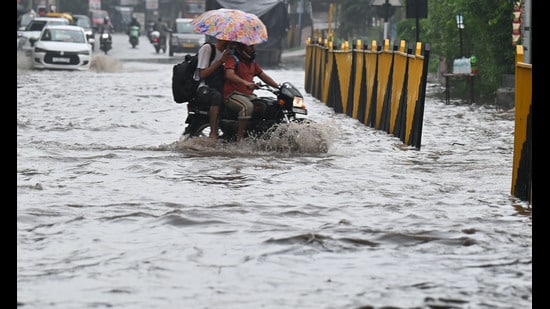 Commuters navigate a waterlogged stretch after Saturday’s rains at Gurugram-Sohna road near sector-68, Airia Mall. (Parveen Kumar/HT)